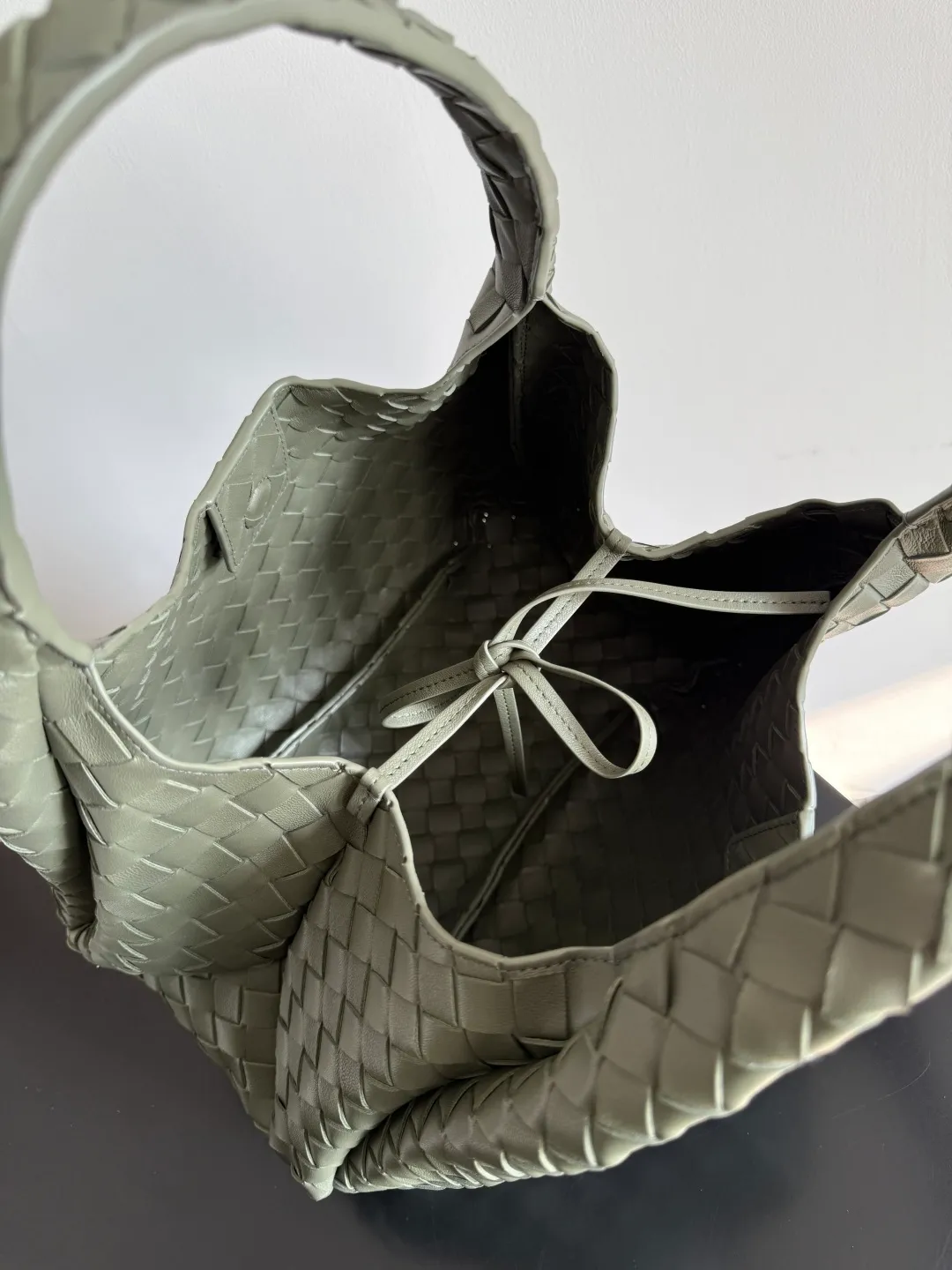 Batch 2160 new products are coming! BOTTEGA VENETA Bottega Veneta's 2025 new Campana shoulder bag is on the market~ First of all, I would like to praise the weight of this bag. As a not too small bag, it is very light for daily use. For people like me who need to carry a lot of belongings when going out, this advantage is great, and it greatly reduces the burden of traveling. 🛍️The shape is a bit like a combination of parachute and jodie. The blunt triangle shape is cute and honest. Carrying it on your back when going shopping is a good mood accelerator. The handles and body of the bag are both classic weaves. A tie is added to the original open design. If it is not tied up, the bag will look like a small vegetable basket when carried. Style number: 844249 Size: 33*20*16.5cm